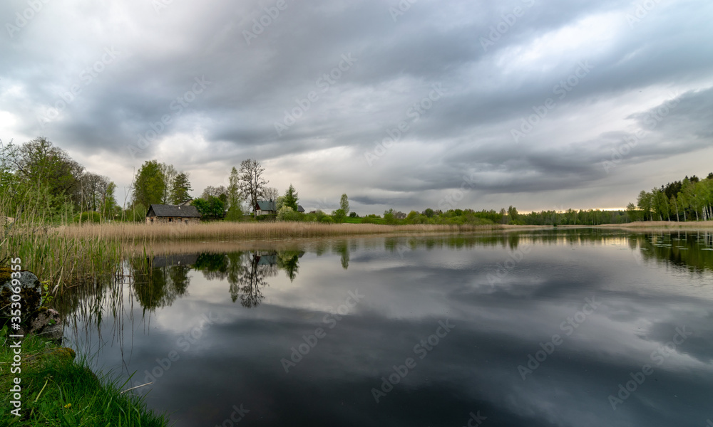 spring landscape with beautiful sky, clouds and tree reflections in the water