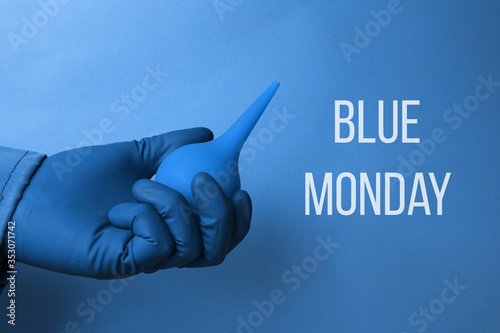 Blue monday text on a blue background and close-up of a hand in a blue glove holding a blue enema. photo