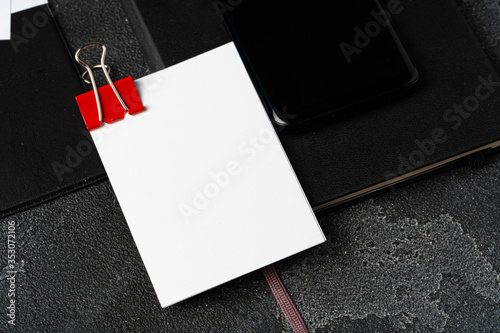 White businesscards united with a paper clip on a black rough background photo