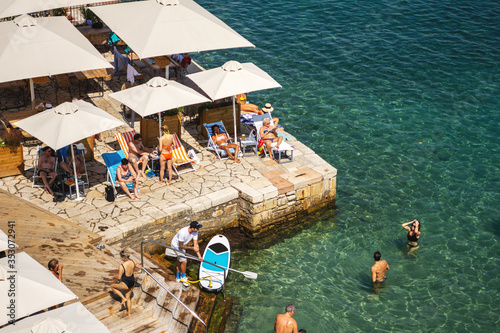 Fototapeta Naklejka Na Ścianę i Meble -  CORFU, GREECE - 10.09.2019 - Faliraki beach Alecos Baths public bathing spot with rock and pier ans restaurant in Corfu Town, Ionian Sea