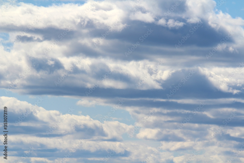 White fluffy clouds on a background of blue sky in summer. The concept of weather and climate. White fluffy clouds on a background of blue sky in summer. The concept of weather and climate.
