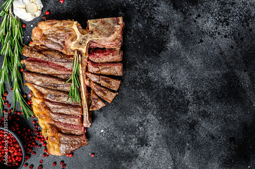 Grilled T-bone steak. Cooked tbone beef. Black background. Top view. Copy space