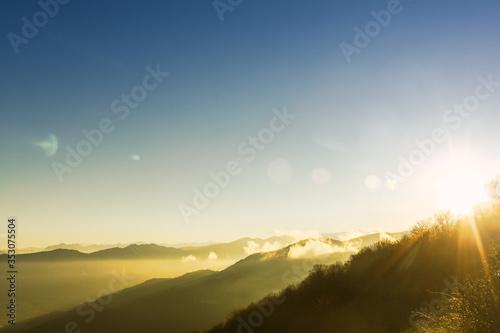 Landscape of mountains at dawn during the sunrise with sun rays crossing them. Time to hiking and traveling