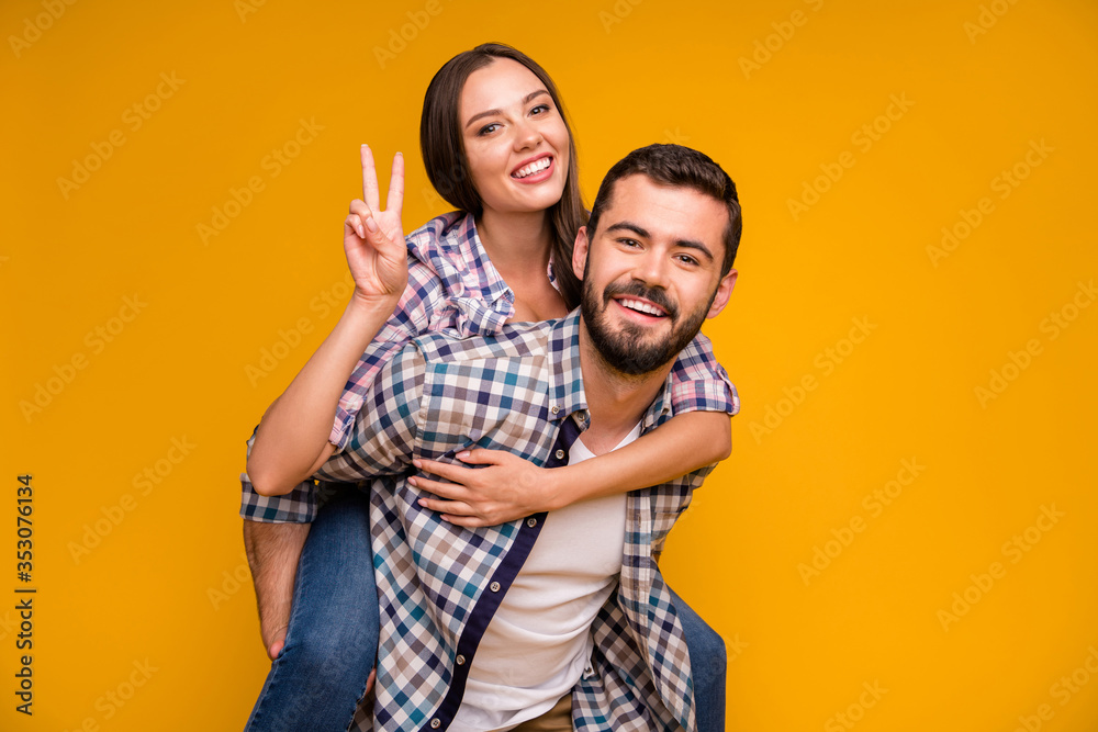 Photo of pretty lady handsome guy couple having fun holding piggyback hands showing v-sign symbol cheerful good mood wear casual plaid shirts jeans isolated yellow color background Photo of pretty lady handsome guy couple having fun holding piggyback hands showing v-sign symbol cheerful good mood wear casual plaid shirts jeans isolated yellow color background