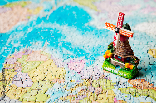 Photography Tourist attractions and souvenir of Amsterdam windmill in background of the world map puzzle for travelers