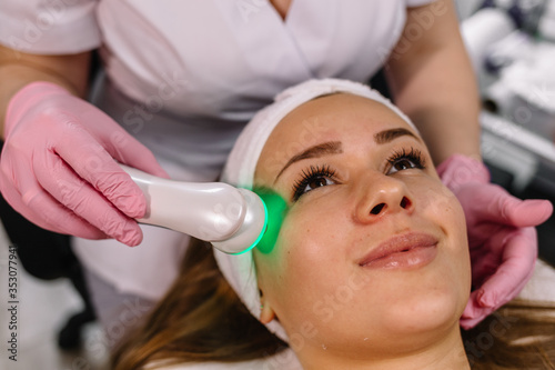 Woman getting laser and ultrasound face treatment in medical spa center, skin rejuvenation concept