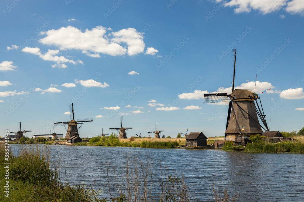 Dutch old windmills, river en blue cloudy sky on landscape, Kinderdijk in South Holland, Netherlands