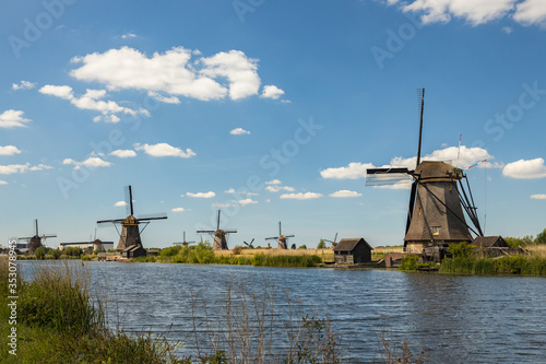 Dutch old windmills, river en blue cloudy sky on landscape, Kinderdijk in South Holland, Netherlands © tselykh