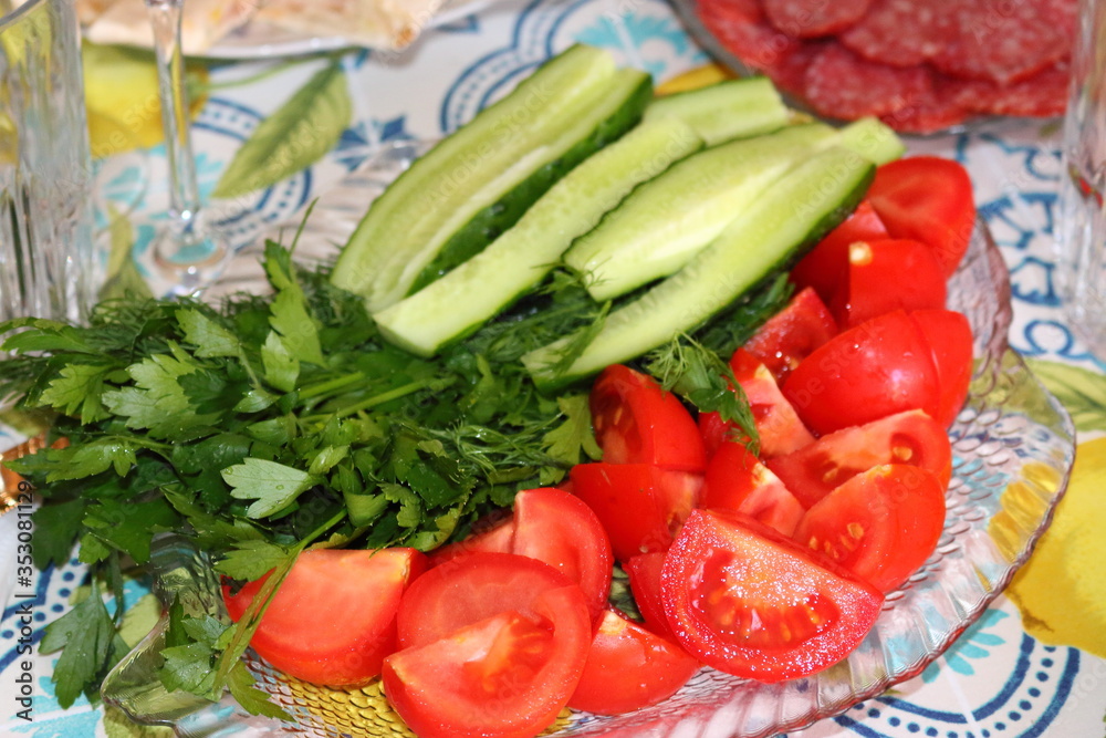 Tomatoes, cucumbers and greens on a glass plate Tomatoes, cucumbers and greens on a glass plate