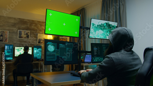 Team of hackers making a dangerous virus for cybercrime. Computer with green screen.
