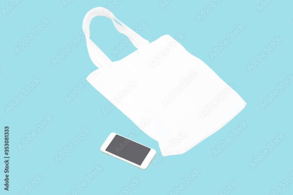 Closeup white bag canvas fabric with smartphone isolated on blue background, Save the world concept Closeup white bag canvas fabric with smartphone isolated on blue background, Save the world concept