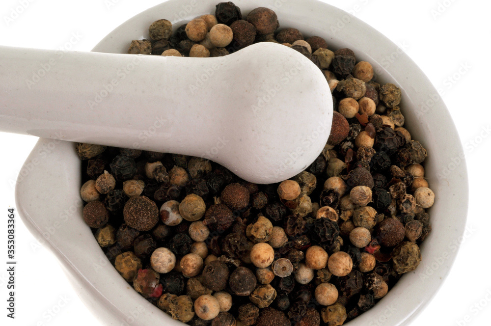 Poivre en grains dans un mortier avec un pilon en gros plan sur fond blanc Poivre en grains dans un mortier avec un pilon en gros plan sur fond blanc