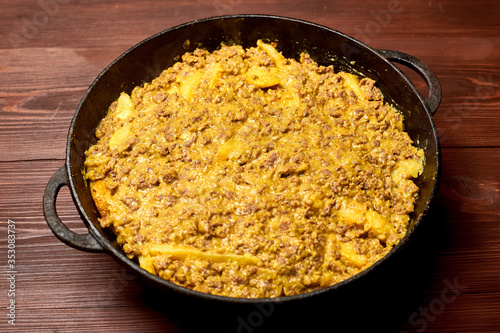 raw casseroles of potatoes and minced meat with cheese in a pan.
