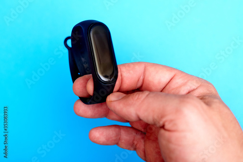 Wristband watch, in a male hand on a blue background. Health monitoring device.