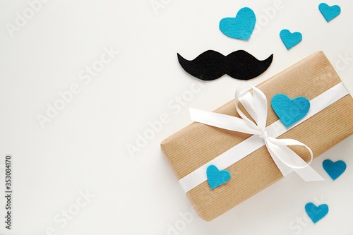 Happy fathers day, gift box with white ribbon, mustache and hearts made of felt fabric, copy space. photo