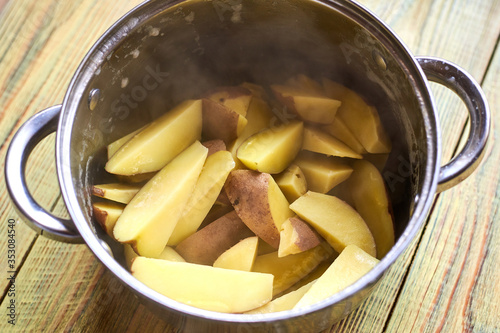 Freshly boiled potatoes in a pan on a wooden background.