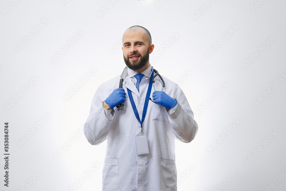 A happy doctor in disposable medical gloves holding a stethoscope. A bald physician with a beard preparing to examine a patient. A happy doctor in disposable medical gloves holding a stethoscope. A bald physician with a beard preparing to examine a patient.