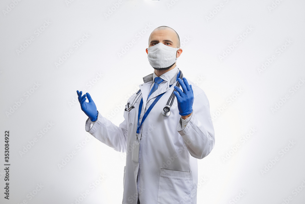 A caucasian doctor in a protective face mask to avoid the spread coronavirus (COVID-19) with hands in disposable medical gloves. A bald physician with a beard preparing to do a procedure. A caucasian doctor in a protective face mask to avoid the spread coronavirus (COVID-19) with hands in disposable medical gloves. A bald physician with a beard preparing to do a procedure.