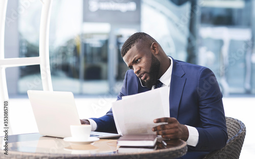 African Businessman Multitasking Talking On Phone Working Sitting In Cafe