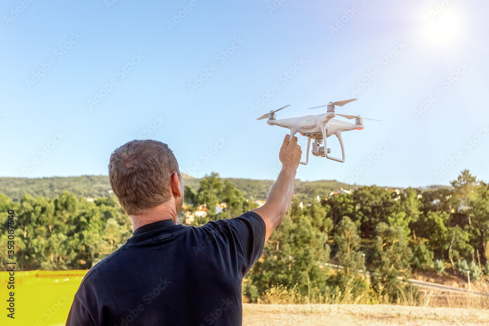 Man, an engineer pilot, a drone, prepares air device for take-off, for testing and filming a vileo and photograph. By controlling the remote.