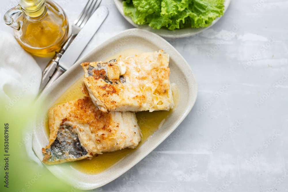 fried cofish with garlic and olive oil on white dish on ceramic background fried cofish with garlic and olive oil on white dish on ceramic background