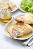 fried cofish with garlic and olive oil on white dish on ceramic background