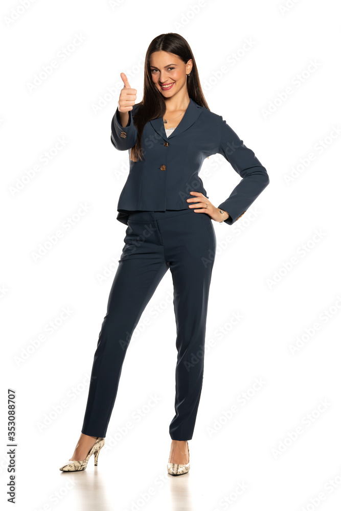 beautiful young smiling business woman in pants and jacket showing thumbs up beautiful young smiling business woman in pants and jacket showing thumbs up