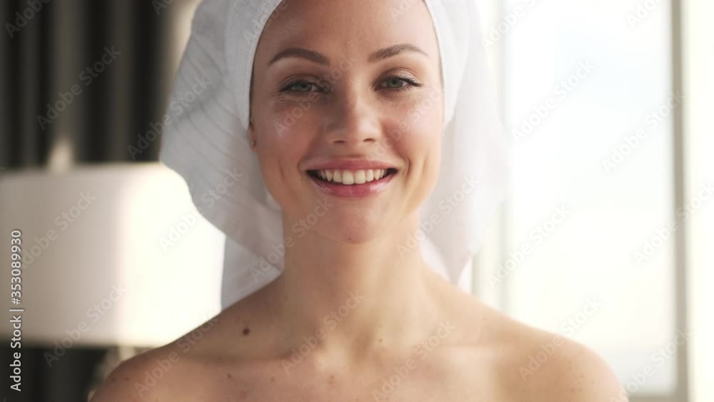 Young pleased positive woman indoors at home with towel on a head