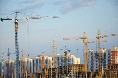Inside place for many tall buildings under construction and cranes under a blue sky working on place with tall homes