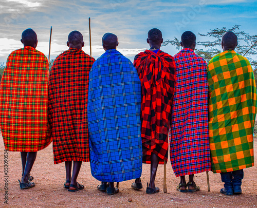 Group of Maasai tribesmen from East Africa with spears and colourful traditional shuka cloth dress (African blanket) looking away from the camera. photo