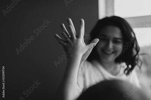 Soft focus. Close up shot of woman hands and her son. Give a five action. She is playing with the baby in bed. Black and white photo