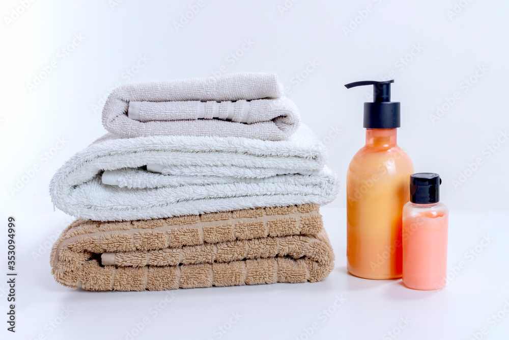 Stack of clean towels with cream and lotion for shower and bathroom treatment. Home spa and relaxation convept on white background Stack of clean towels with cream and lotion for shower and bathroom treatment. Home spa and relaxation convept on white background