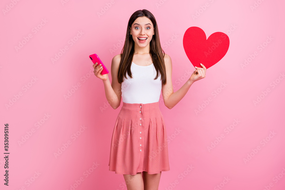 Photo of attractive amazed lady hold telephone red paper heart check likes instagram wear casual white singlet short summer dotted skirt isolated pastel pink color background Photo of attractive amazed lady hold telephone red paper heart check likes instagram wear casual white singlet short summer dotted skirt isolated pastel pink color background