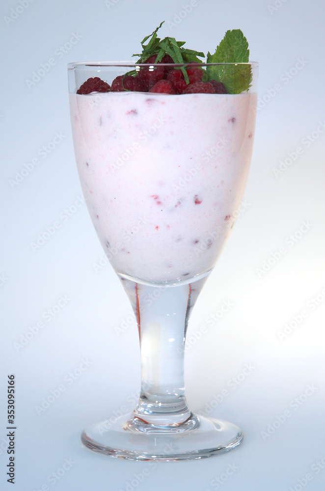 Yogurt with raspberries in a clear glass decorated with mint on a white background Yogurt with raspberries in a clear glass decorated with mint on a white background