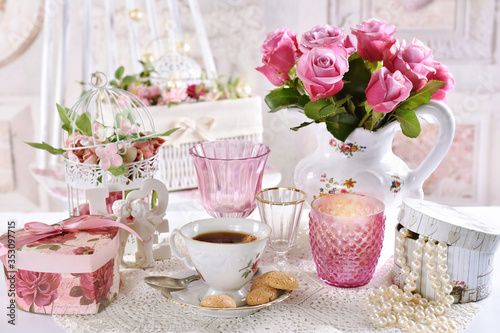 bouquet of pink roses in jug on the table with coffee and gift boxes