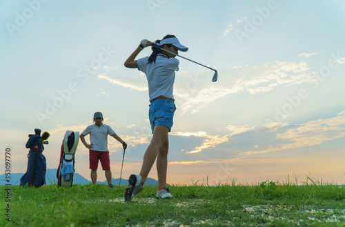 Couple in action of playing golf together. Obstacles to golf drills in rough areas and difficult drills. Difficult time stay together in the family course. Beautiful nature silhouette.
