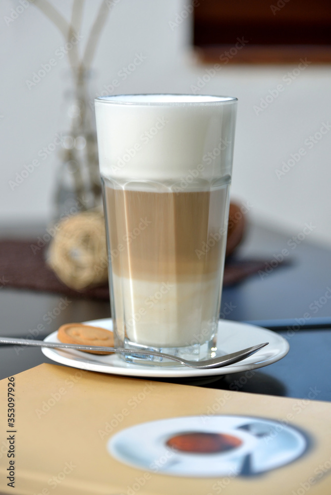 Cappuccino with foam on wooden table with drink menu in foreground Cappuccino with foam on wooden table with drink menu in foreground