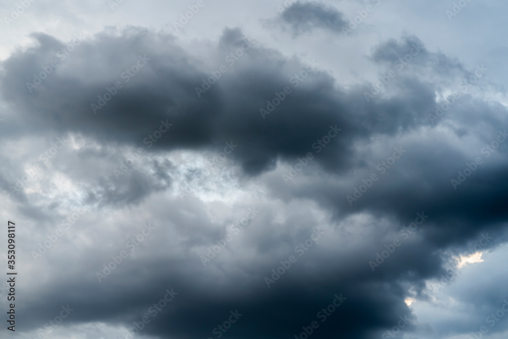 Bad weather with the sky completely covered by gray and black rain clouds placed in several layers, dark atmosphere with nimbus and cumulus clouds. Climate change causes extreme weather events.