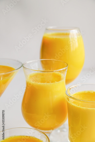 Golden milk with turmeric in different glasses on white background. Healthy spicy curcuma drink concept. Trendy minimal food