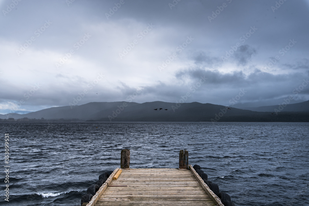 wooden dock in the lake with raining at mountain background