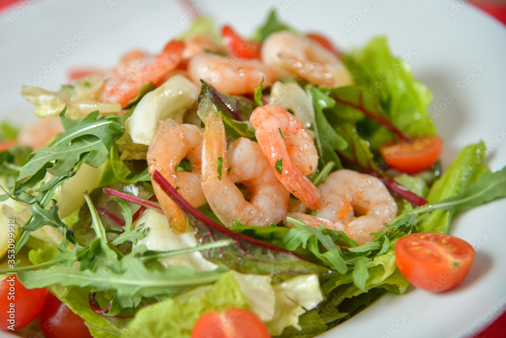 Vegetable salad with shrimp on white plate on red-white tablecloth Vegetable salad with shrimp on white plate on red-white tablecloth