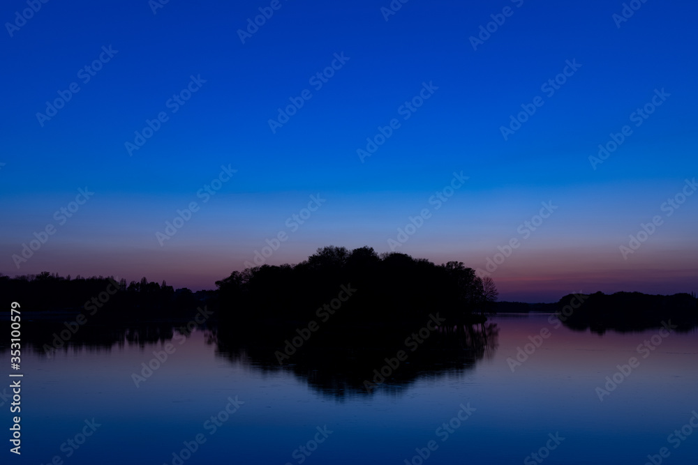 twilight landscape after sunset scenic view horizon silhouette of land with peaceful waters and reflection surface island and trees center of composition, dark blue sky lighting