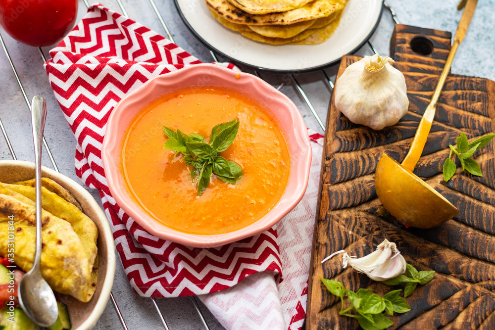 Orange pumpkin carrot creamy vegetables soup in bowl with rucola herb on top. Vegan food lunch