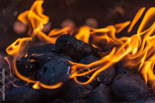 Grill briquettes that are burning and waiting to be glowed for grilling, Briquettes are made from lignite, peat, charcoal or coal stub photo