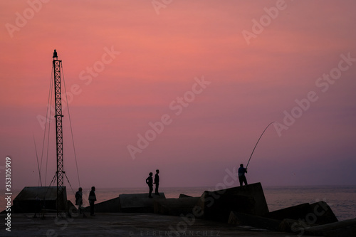 Pescador al atardecer un dia de verano pesca junto a la orilla