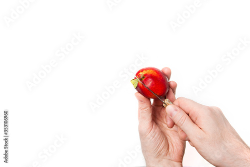 male hands cutting ripe nectarine with a knife isolated on a white background