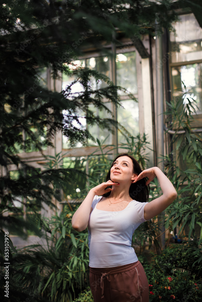 A beautiful young girl walks through an old greenhouse. Woman in the Botanical garden A beautiful young girl walks through an old greenhouse. Woman in the Botanical garden
