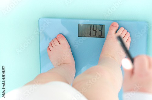 Toddler is standing on bathroom scales. View from above. Child health care