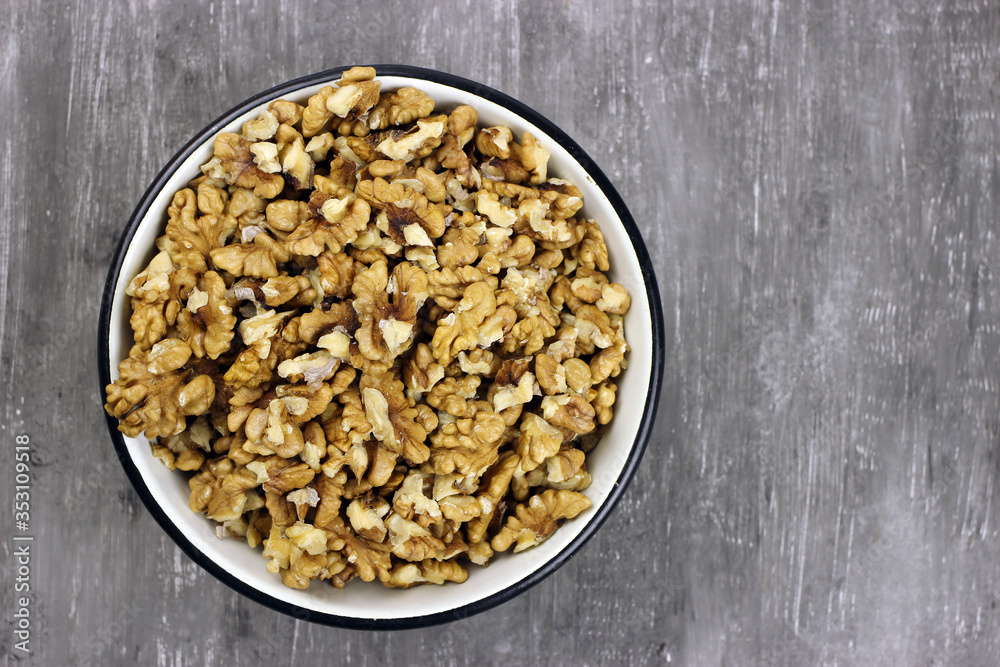 walnut kernels in a bowl on a gray background top view