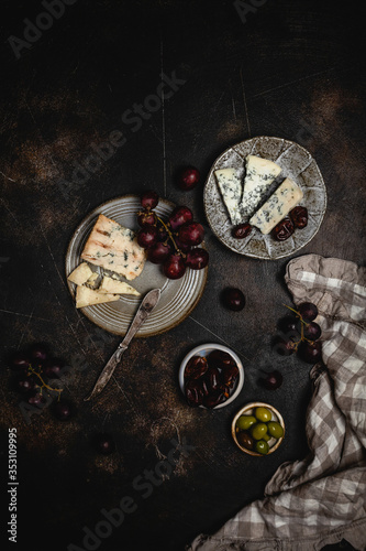 Blue cheese and grape, olives and dates on grey plate with knife on brown concrete background, copy space, wine snack photo